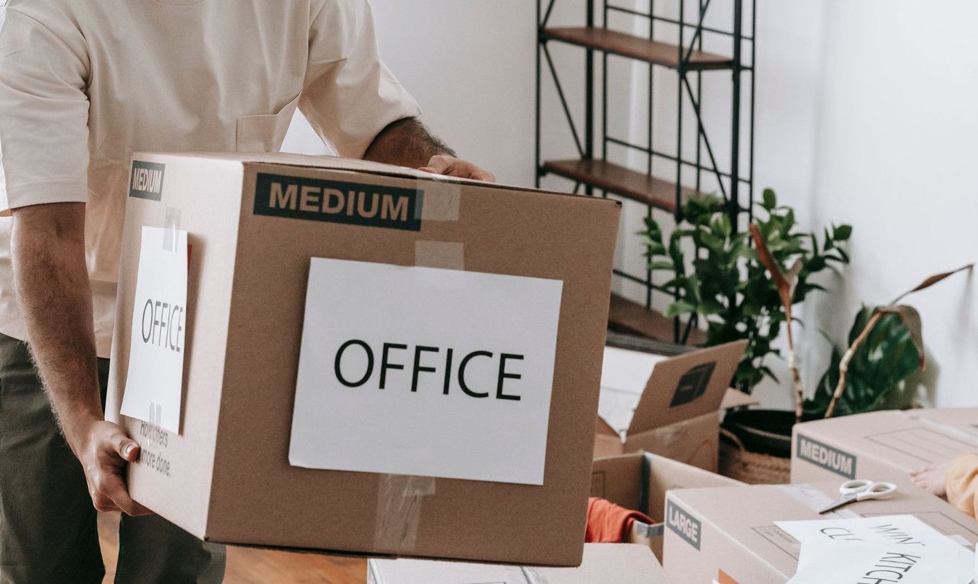 A joyful couple packing boxes labeled 'office' in their home, preparing to move.